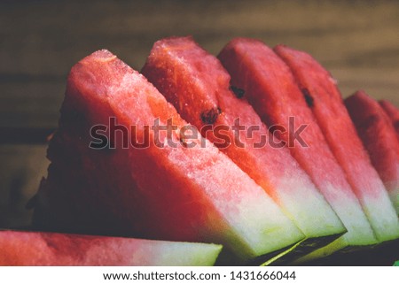 Fresh slices of a ripe watermelon on a plate on a wooden background.
