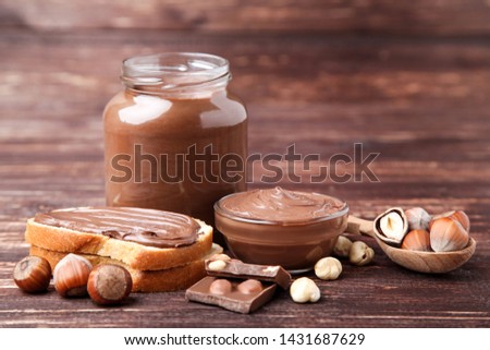 Bread with melted chocolate and hazelnuts on brown wooden table