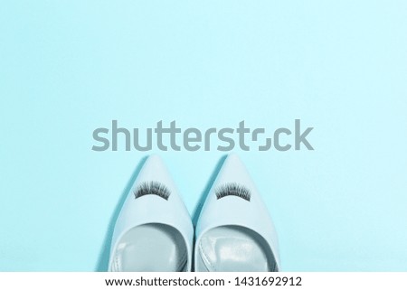 High heeled shoes with eyelashes on blue background. Minimalism concept
