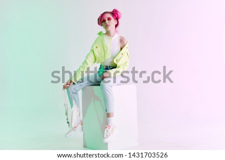 woman with pink hair in trendy clothes sits on a cube