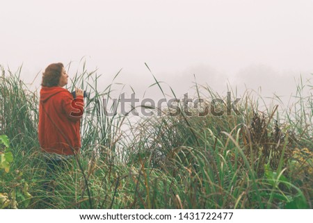 Woman photographer photographs the fog on the lake