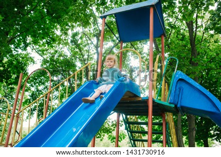 Child girl on slide in playground. Outdoor park