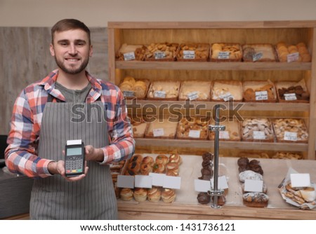 Smiling seller holding payment terminal in bakery. Space for text