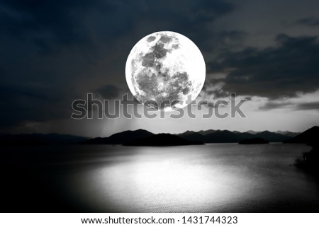 Bright full moon over lake in the dark night.