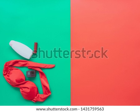 Summer accessories and Women's Clothing concept from red bikini, Action camera and cosmetics on background pastel color green and red for advertising selling products.