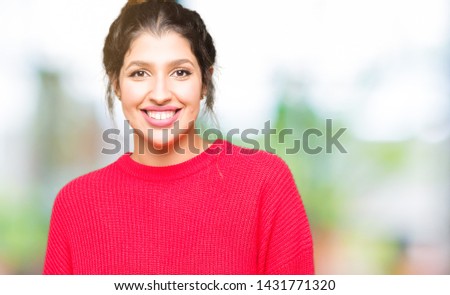 Young beautiful woman wearing red sweater and bun with a happy and cool smile on face. Lucky person.