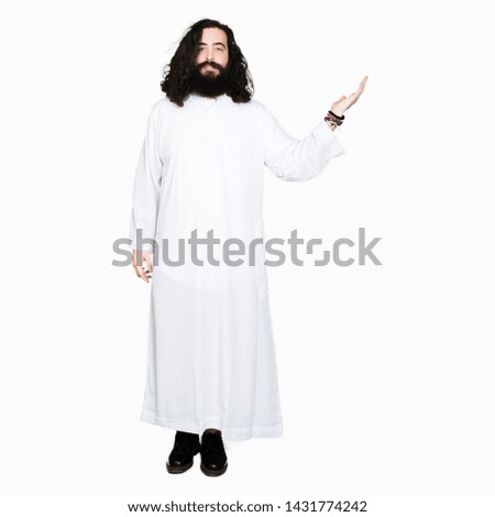 Man wearing Jesus Christ costume smiling cheerful presenting and pointing with palm of hand looking at the camera.