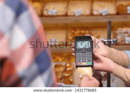 Man using bank terminal for credit card payment in bakery, closeup