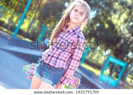 portrait of a little teenage girl, walking down the street, holding a colorful skateboard, active lifestyle of children