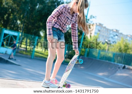 portrait of a little teenage girl, holding in hand skateboard, trains to do the trick