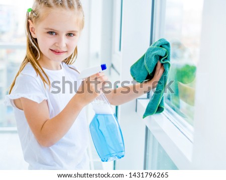 Cute little girl helping parents with cleaning the window with spray