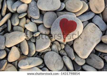 I love you and stone heart painted with a red paint marker on the pebble as a gift for Saint Valentine day on the pebble background.