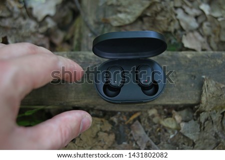Black Bluetooth in-ear headphones outdoors in the Park
