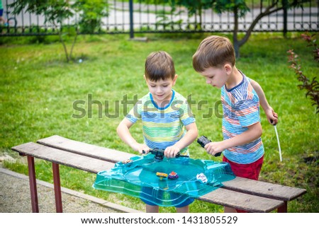 Two Boys playing with modern spin top outdoors. Entertainment game for children. Top, triggered by a trigger. Kids having a tournament on arena or battle field.
