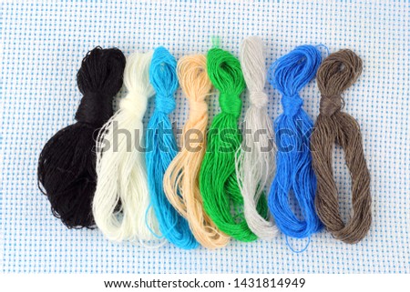 A set of multi-colored threads for embroidery in small hankov on a light background.