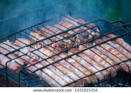Meat barbecue. Sausages with cheese spun in bacon on a metal grill close-up.