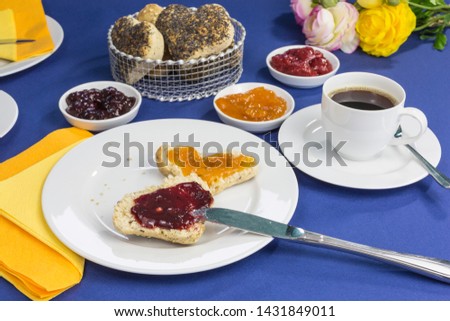 breakfast table with freshly baked heart shaped buns, different jams and coffee