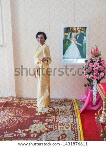 Beautiful asian bride in Traditional Thai Costumes. She is standing in the living room. 