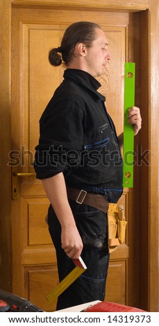 Young carpenter with tools belt holding level instrument and protractor