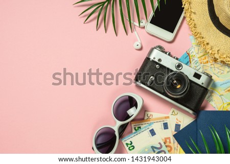 Travel concept. Summer holiday trip background. Old film camera, hat, money and palm leaves on pink background. Top view. Flat lay.