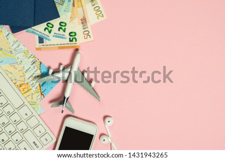 Trip planning background. Laptop, map, cash money, map and airplane on pink background. Top view. Flat lay.
