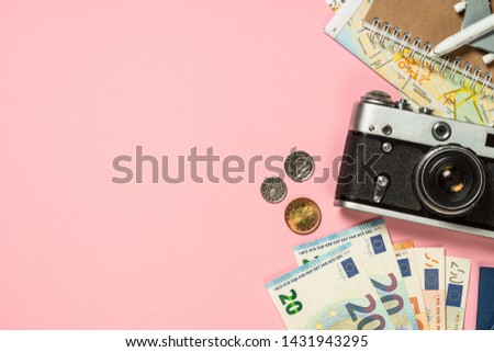 Travel Trip background flat lay. Old film camera, map and cash money on pink background.