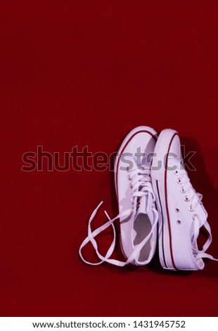 some white sneakers are on the other on a red background with laces