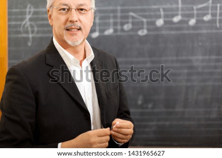 Senior music teacher against a blackboard with notes