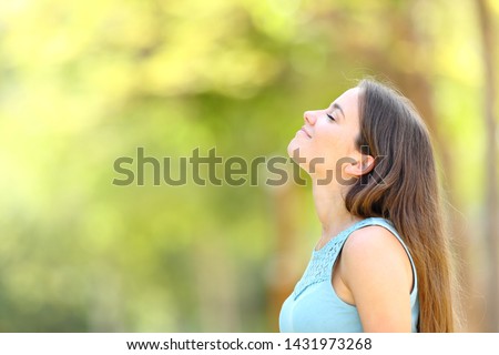 Profile of a woman breathing deeply fresh air in a forest with a warm green background Royalty-Free Stock Photo #1431973268