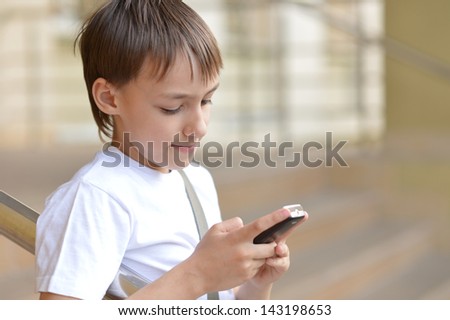 young boy playing in the game on the a phone outdoors