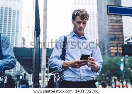 Caucasian employer searching information on smartphone with 4g wireless for browsing internet, intelligent male business trader chatting on cellular gadget while spending day in financial district