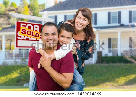 Happy Mixed Race Family In Front of House and Sold For Sale Real Estate Sign.