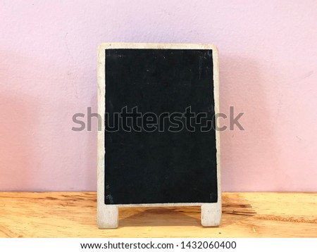 A mini blackboard on wooden table in a cafe’. This blackboard is write special menu. A blackboard is little dirty after erase message. Background is pink cement wall. There is copy space for texture.