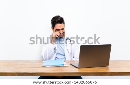 Young doctor man with his laptop over isolated wall laughing