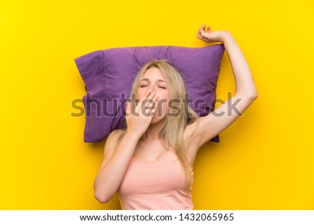 Young blonde woman in pajamas yawning