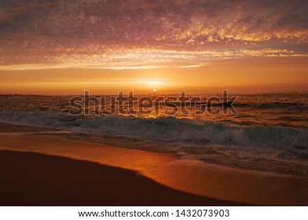 Reflections on water at sunset on the beach as waves break on the sand