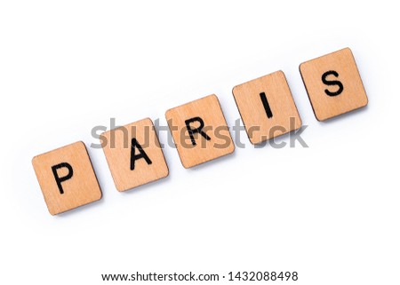 The word PARIS, spelt with wooden letter tiles over a white background.