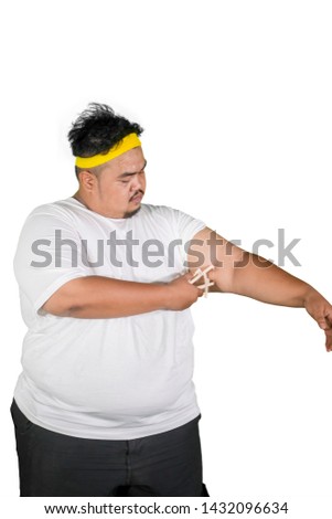Picture of young man measuring fat layer of his arm by using calipers in the studio, isolated on white background
