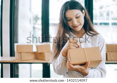 happy women write the name and address of the customer to send through the shipping company, online business concept, business owner concept
