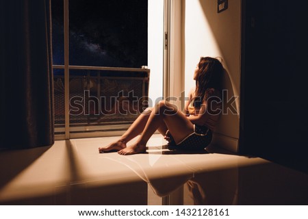 Sad and depressed young woman sitting on the floor in the living room looking outside the doors,sad mood,feel tired, lonely and unhappy concept. Selective focus Royalty-Free Stock Photo #1432128161