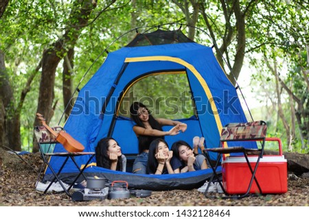 Happy group women on a camping trip relaxing in tent.checking photo