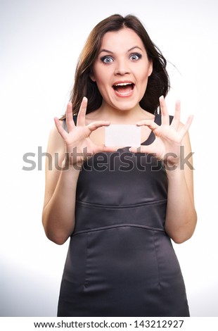 Surprised young woman in a gray business dress. Woman holds a poster. On a white background