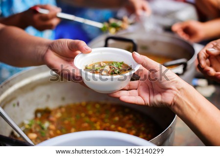 Homeless people are helped with food relief, famine relief : volunteers giving food to poor people in desperate need : The concept of food sharing Help solve Hunger for the homeless Royalty-Free Stock Photo #1432140299