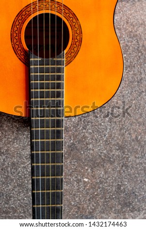Wooden six-string guitar. Close-up of a guitar lying on a concrete background