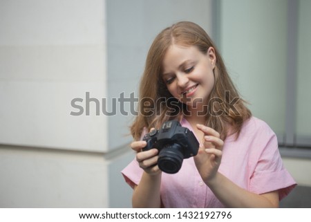 Portrait of young caucasian woman photgrapher holding a digital camera, taking photo or video