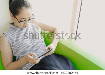 Asian woman concentrate on playing mobile game on the sofa.