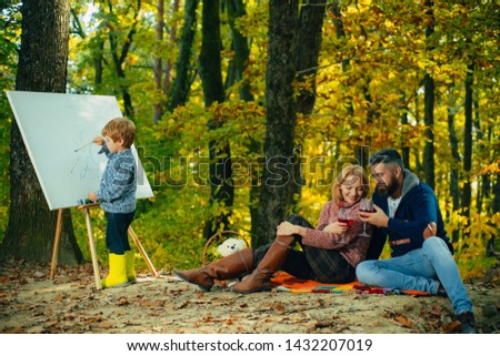 Painting skills. Mom and dad relax park picnic while kid painting. Rest and hobby concept. Parents watching their little son painting picture in nature. Art and self expression. Talent development.