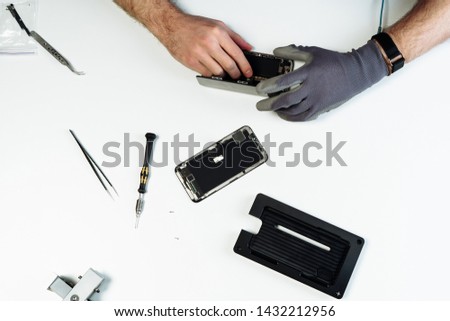 Man Repair Disassembled Broken Smartphone Flat Lay. Engineer Hands in Glove Dismantle Smartphone and Service Equipment on White Background. Process Fix Maintenance Telephone Device