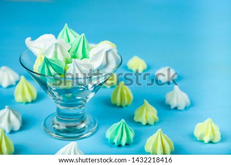 Meringue in a transparent bowl on a blue  wooden background. Delicious dessert. Colorful handmade meringue.