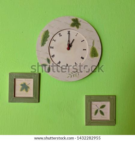 Green wall with clock and pictures - One o’clock